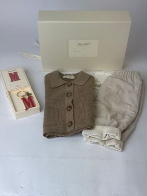 une photo d'une tenue pour petit garçon et d'un lot de couches présentés dans une boîte