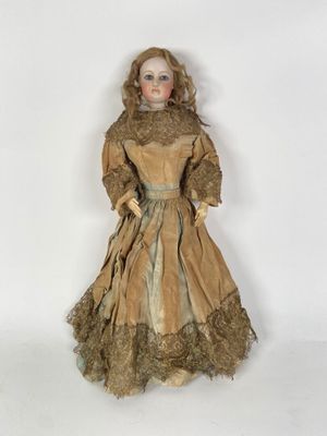 une poupée à l'ancienne, vêtue d'une robe marron et d'un chapeau marron