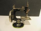 une machine à coudre noire et verte posée sur une table blanche
