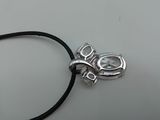 a close up of a necklace on a white surface with a black cord
