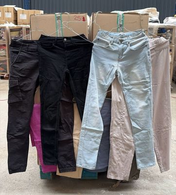 Plusieurs paires de pantalons sont empilées sur un chariot dans un entrepôt