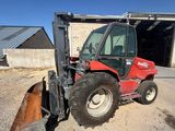 un tracteur rouge garé devant un bâtiment équipé d'une lame à neige