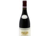 the bottle of red wine is sitting on a white surface