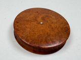 a round wooden box with a button on top of it