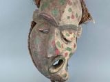 une image d'un masque en bois accroché au mur