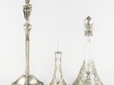 two silver candlesticks and a glass vase on a white background