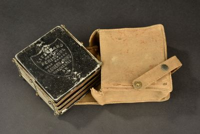 un vieux livre posé sur une mallette en cuir, à côté d'une pile de livres
