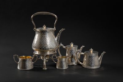 a group of silver tea and coffee pots on a black background