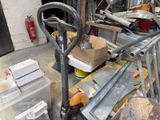 un tas de bric-à-brac dans un garage, avec une fourche et d'autres objets
