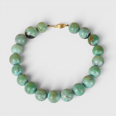 un gros plan d'un bracelet orné de perles vertes sur fond blanc
