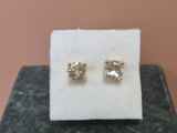a pair of diamond stud earrings sitting on top of a white cloth