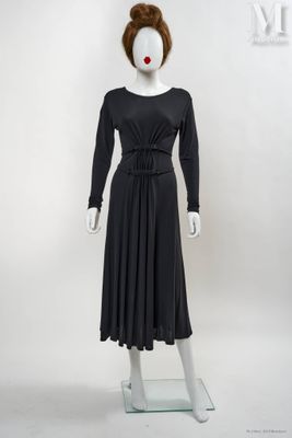 Le mannequin porte une robe noire et du rouge à lèvres rouge.