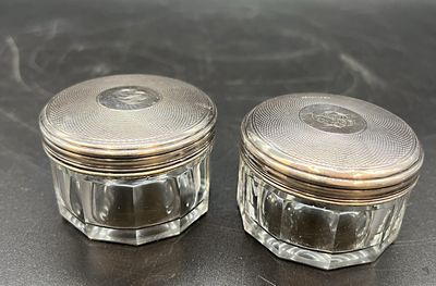 deux petits bocaux en verre avec des couvercles argentés posés sur une table
