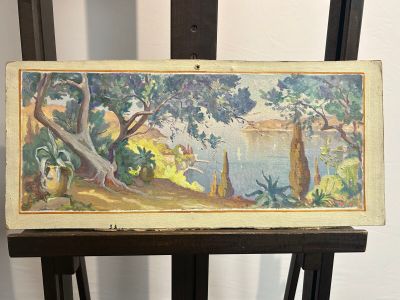 painting on a wooden easel with a painting of a lake and trees