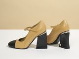 a pair of beige and black shoes with pearls on the heel