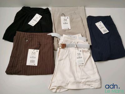 Quatre paires de pantalons de costume pour homme sont alignées sur une table