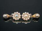 a pair of pearl and gold earrings on a black surface