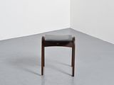 a small wooden chair with a black seat in a white room