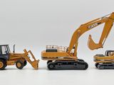 three toy construction vehicles sitting next to each other on a white surface