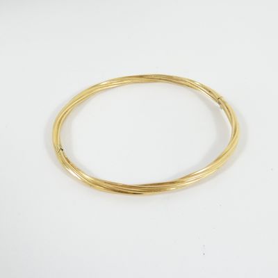 gros plan d'un bracelet en or sur une surface blanche