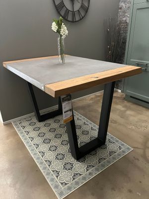 La table est en béton et en acier, avec un plateau en bois.