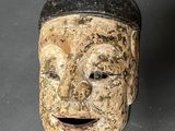 a wooden mask hanging on a wall on a table