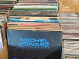 vinyl records in a cardboard box on a table in front of a wall