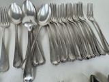 a lot of silver spoons and forks laid out on a table