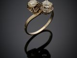 a gold ring with two diamonds on a black surface