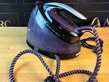 un fer à repasser à vapeur noir et violet posé sur une table en bois