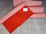trois rouleaux de tissu rouge posés sur un parquet