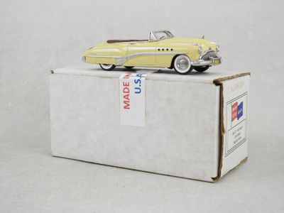 une petite voiture jaune posée sur une boîte en carton, sur une surface blanche
