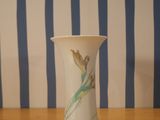 a white vase sitting on a wooden table with blue and white stripes