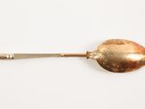 a silver spoon with a gold handle on a white surface