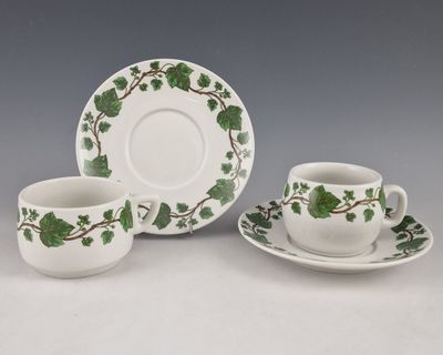 deux tasses et soucoupes ornées de feuilles vertes, posées sur une table