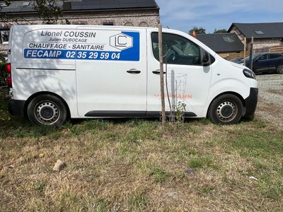 une camionnette garée devant un immeuble sur lequel est accrochée une pancarte