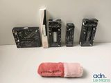 three boxes of mascaras and a pink towel on a table