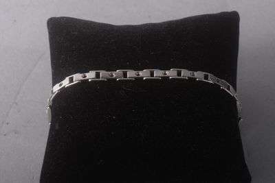 silver bracelet on a black cushion on a white surface