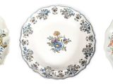 trois assiettes ornées de motifs floraux sont alignées sur une surface blanche