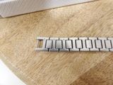 a silver bracelet sitting on a wooden table next to a white box