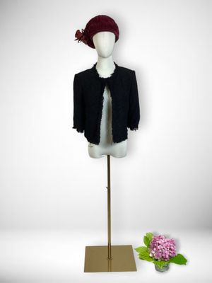 black jacket on a mannequin stand with a pink flower in front of it