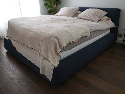 a bed with a blue headboard and a beige comforter