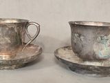 deux tasses et soucoupes en argent posées sur une table