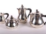 three pieces of silver tea and coffee set on a white surface