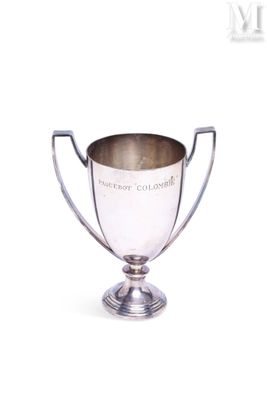 coupe de trophée plaquée argent posée sur un socle, sur fond blanc