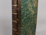 an old book with a green cover sitting on a table