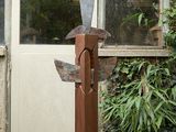 une sculpture représentant un oiseau, posée sur un socle devant un bâtiment