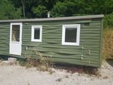 une petite maison verte avec une porte et des fenêtres blanches
