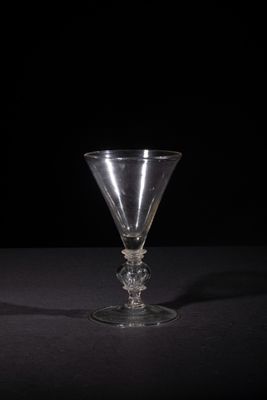 a wine glass sitting on a table with a black background