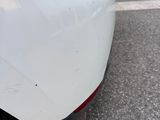 the rear end of a white car parked on the side of the road